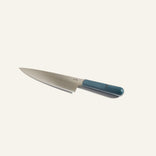A stainless steel chef’s knife with a blue handle is positioned on a plain white background.