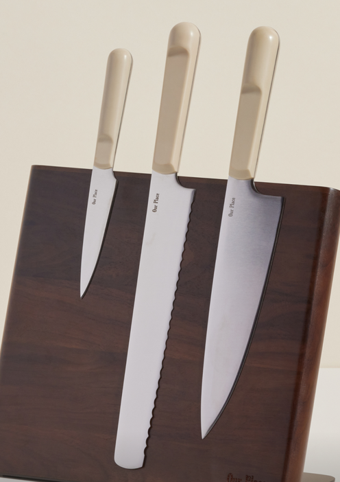 Three kitchen knives with beige handles in a dark wooden knife block, displayed upright against a light background.