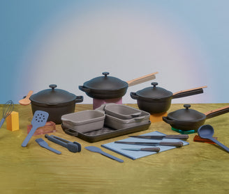 A collection of cookware and utensils, including pots with lids, baking dishes, a whisk, spatulas, tongs, and ladles, arranged on a table with a blue and green background.