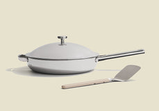 White ceramic cookware set with a spatula on a beige background