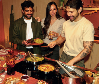 People cooking, drinking, and eating over a countertop