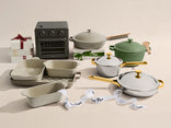 Collection of kitchenware including pots, pans, and a small oven on a beige background.