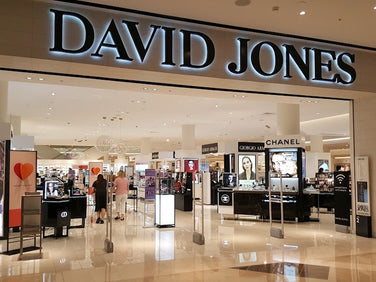 Entrance to a David Jones department store, showing displays for beauty and fragrance brands inside a well-lit shopping mall.