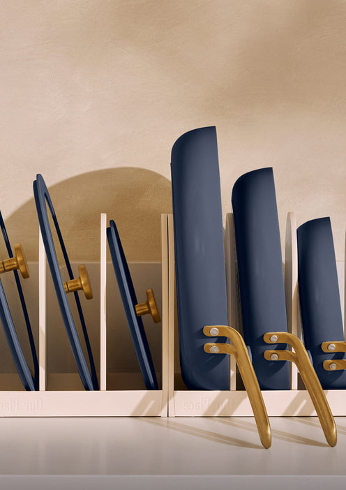 Set of blue cookware in a white holder with gold accents on a beige background