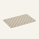Checkered bath mat with beige and white squares on a light beige background