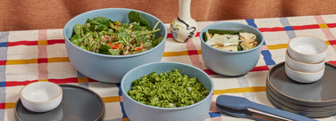 blue better bowl set, blue tongs, white mini bowls and black salad plates set on table