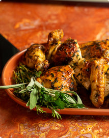 Roasted chicken pieces with fresh herbs on an oval ceramic platter.