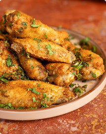 A plate of seasoned chicken wings garnished with chopped fresh herbs.