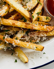 French fries topped with grated cheese and herbs, served with a side of ketchup.
