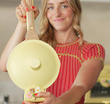 Woman holding a yellow toy pan with a wooden handle