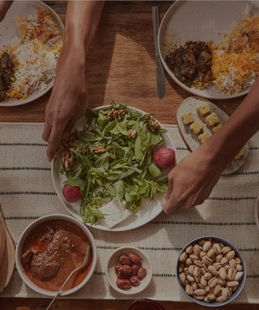 People sharing a meal at a table with various dishes and drinks.