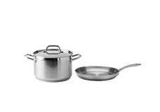 A stainless steel stock pot with a lid and a stainless steel frying pan are placed side by side on a plain white background.