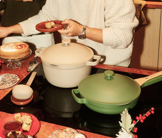 Person holding a red plate with food near two pots on a stove.