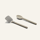 A stainless steel spatula and a tan serving spoon from a Titanium Pro Utensil Set.