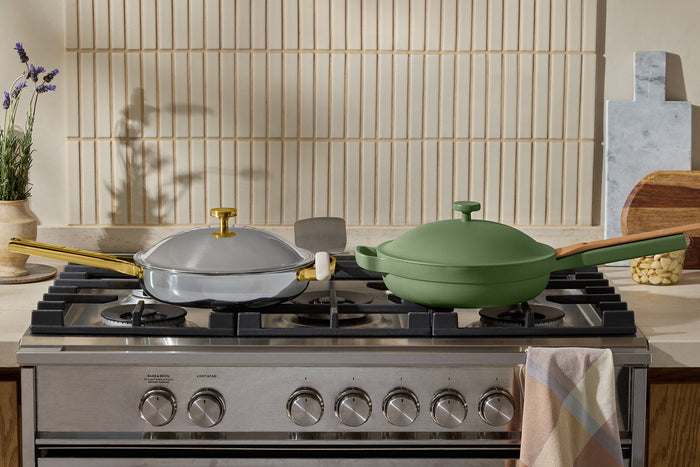 A chrome/gold pan and a green pan on a stovetop
