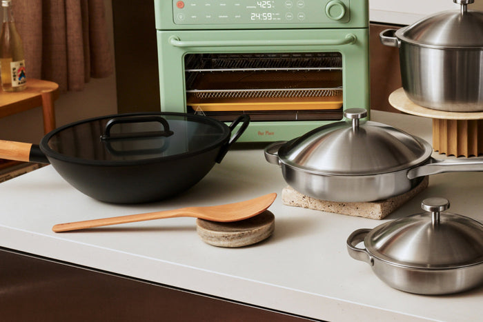 Wok, stainless steel pan, and light green small oven on a countertop