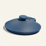 A blue silicone hot water bottle with a wide, round shape and a central cap, placed on a light background.
