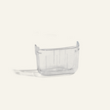 A small, clear plastic container with slightly raised sides sits on a plain, light-colored background.