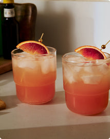 Two cocktails with blood orange slices on a light surface