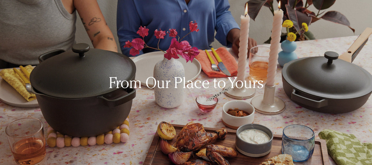 Translation missing: en.Two people sit at a decorated table set with cookware, flowers, candles, drinks, and a meal featuring roasted chicken, potatoes, and various sauces. Text reads, “From Our Place to Yours.”