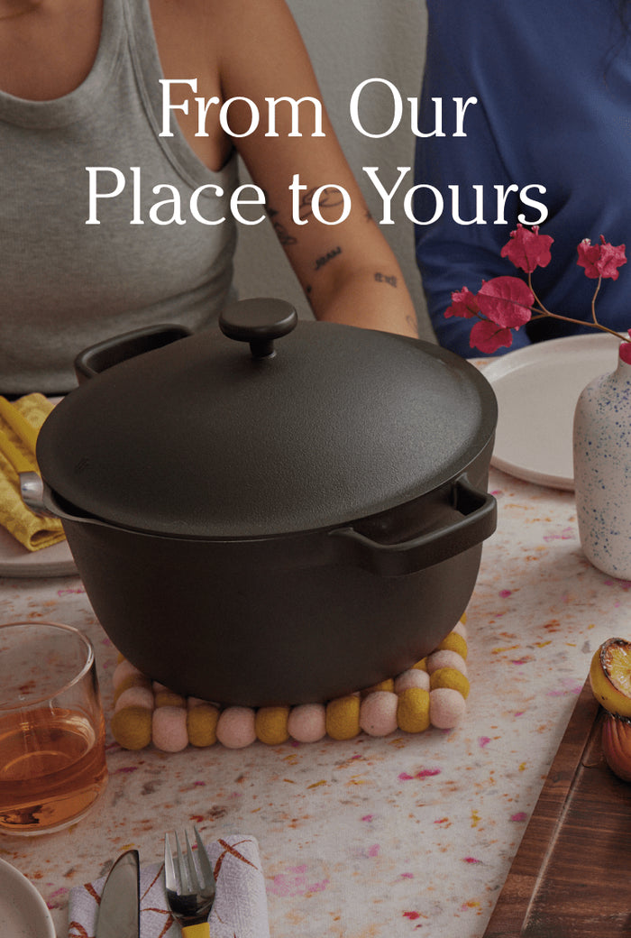Translation missing: en.A black Dutch oven sits on a trivet at a set dining table with drinks, plates, and a vase of pink flowers. Text reads: From Our Place to Yours