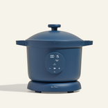 A blue electric multi-cooker with a digital display showing 00:15 and simple touch controls, sitting on a matching base against a plain background.