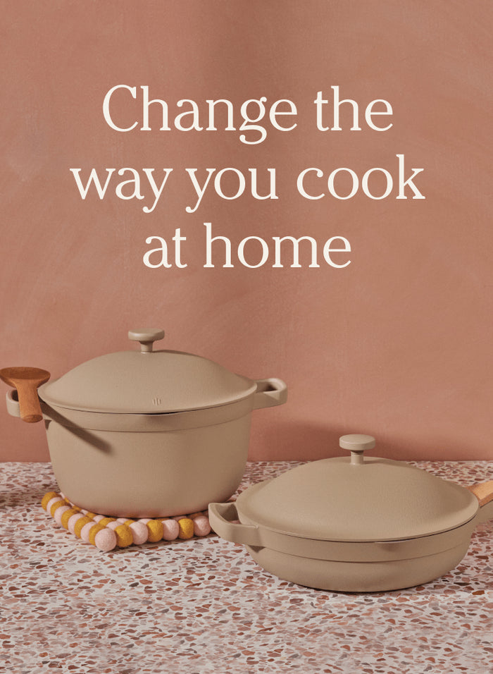 Translation missing: en.Two beige cookware pieces with lids and wooden handles are displayed on a speckled countertop with the text Change the way you cook at home above them