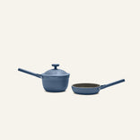 The Tiny Cookware Duo, featuring a non-toxic blue saucepan with lid and a matching blue frying pan inspired by the Always Pan, sits side by side on a plain, light background.