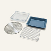 The Wonder Oven Pro Chef’s Kit includes a rectangular blue baking pan, wire cooling rack, mesh basket, and round perforated tray on a white background.
