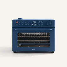 Wonder Oven Pro: Blue countertop 8-in-1 air fryer oven with digital display, control knobs, buttons, and glass door showing versatile interior racks.