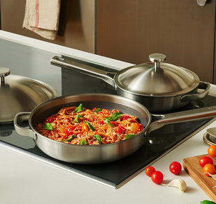 titanium cookware set on a stove with pasta and vegetables.