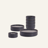 The Complete Plates & Bowls Set features chip-resistant, dark ceramic dinnerware—stackable plates, bowls, and small dishes—neatly arranged on a light background. Stylish design makes it perfect for daily use.