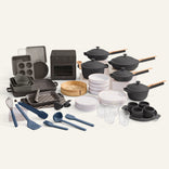 A set of black cookware and bakeware and a black oven on a white background