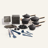 A set of black cookware, a black oven, and blue cooking utensils on a white background