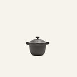 The Petite Perfect Pot, a black, round nonstick pot with dual handles and a lid, ideal for personal servings, is centered on a plain off-white background.