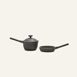 The Tiny Cookware Duo, featuring a black Perfect Pot with lid and long handle alongside a matching Always Pan, both non-toxic, sits on a plain light background.