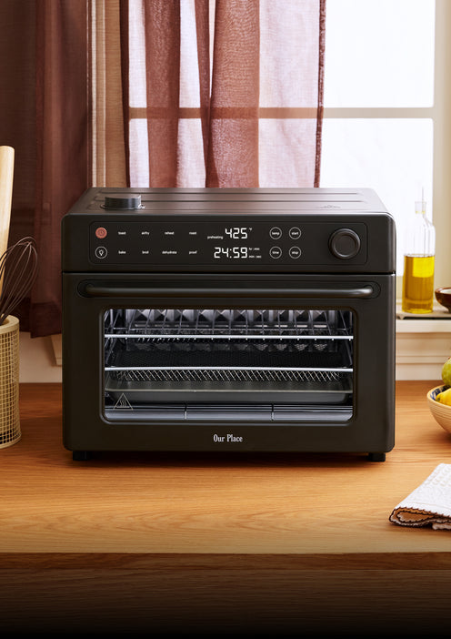 Black Our Place countertop oven with a digital display showing a temperature of 425 degrees and a timer set to 24:59.