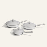 Three lidded stainless steel pans of varying sizes from the Titanium Pro Always Pan Trio 2.0 set, arranged in a cluster.