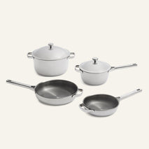 Two pots with lids and two skillets with metallic interiors and light-colored exteriors, displayed as a Titanium Pro Cookware Set 2.0.