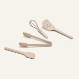 The Mini Utensil Essentials set features five beige silicone tools—a whisk, spatula, slotted turner, tongs, and another spatula—on a light background.