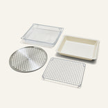 The Wonder Oven Pro Chef’s Kit includes a rectangular mesh basket, baking pan, round perforated tray, and rectangular wire cooling rack on a white background.