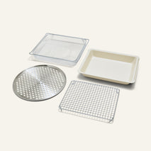 The Wonder Oven Pro Chef’s Kit includes a rectangular mesh basket, baking pan, round perforated tray, and rectangular wire cooling rack on a white background.