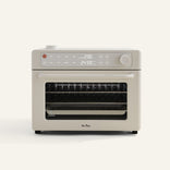 The Wonder Oven Pro is a beige toaster oven with digital controls, a knob, a pull-down door labeled Our Place, and also works as an air fryer.