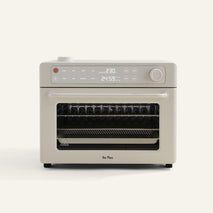 The Wonder Oven Pro is a beige toaster oven with digital controls, a knob, a pull-down door labeled Our Place, and also works as an air fryer.