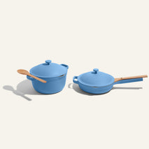 The Cookware Duo—featuring a blue pot and pan, each with its own lid and wooden spoon—sits side by side on a light background, making it the perfect kitchen upgrade.