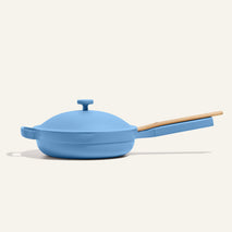 The Always Pan 2.0, a bestselling light blue nonstick frying pan with a matching lid and light wooden handle, is displayed against a plain off-white background.