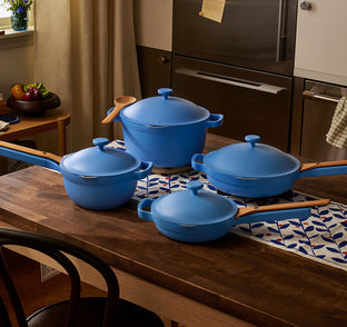 Set of blue cookware on a kitchen counter with a stove in the background