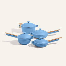The four-piece Cookware Set features blue pots with matching lids and wooden handles, displayed on a light background—perfect for fans of the Always Pan or Perfect Pot collections.