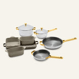 Titanium Pro Cookware + Bakeware Set 2.0 featuring stainless steel pots, frying pans, and baking dishes with gold-colored handles and lids.