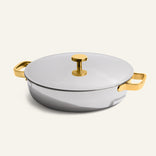 Introducing the Titanium Braiser Pro 28 cm—a round stainless steel Dutch oven with a lid, featuring gold-colored handles and a gold knob. Set against a plain light background, this chef-approved braiser combines elegance and durability, making it an essential addition to any kitchen.